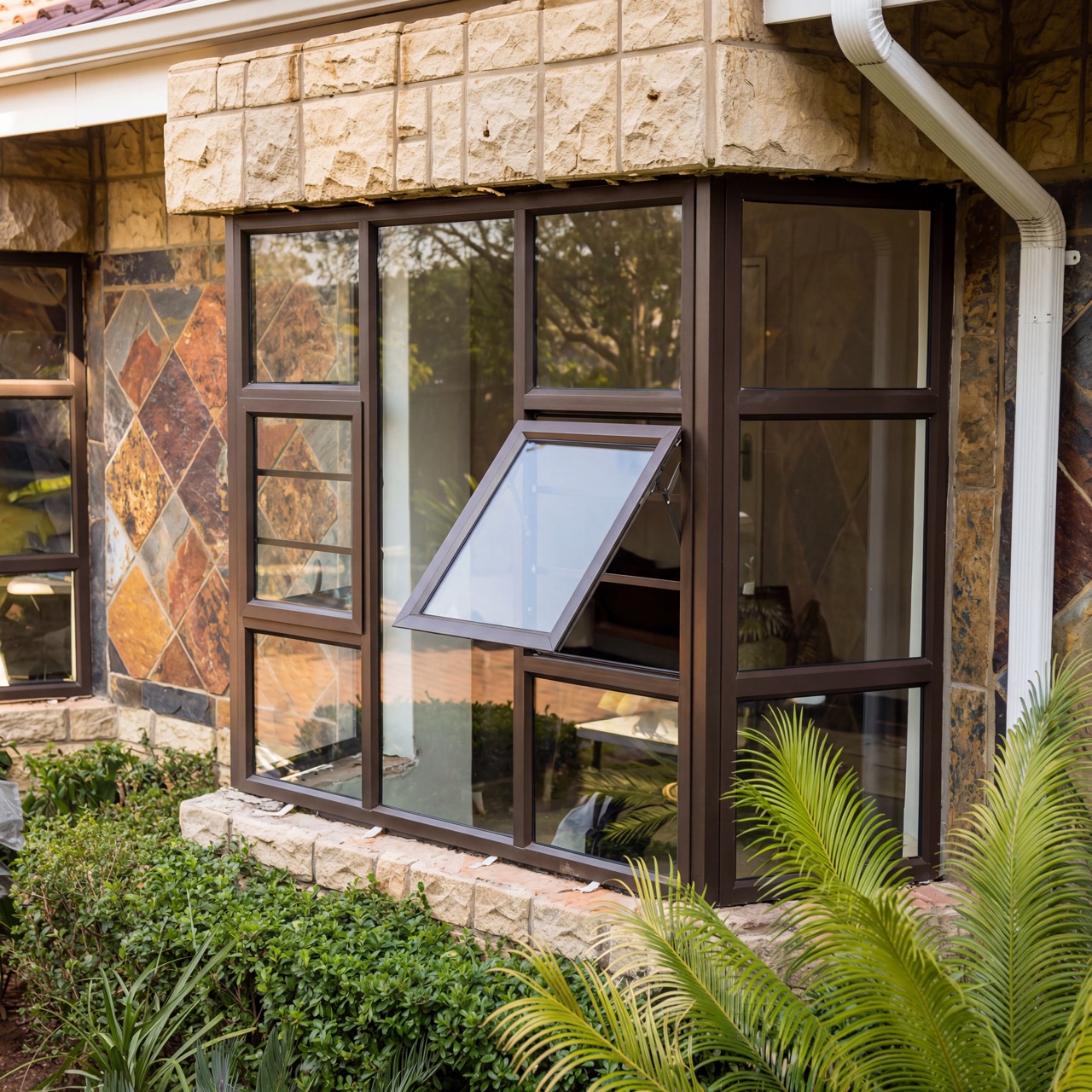 Stone-clad corner window installation with black aluminium frames