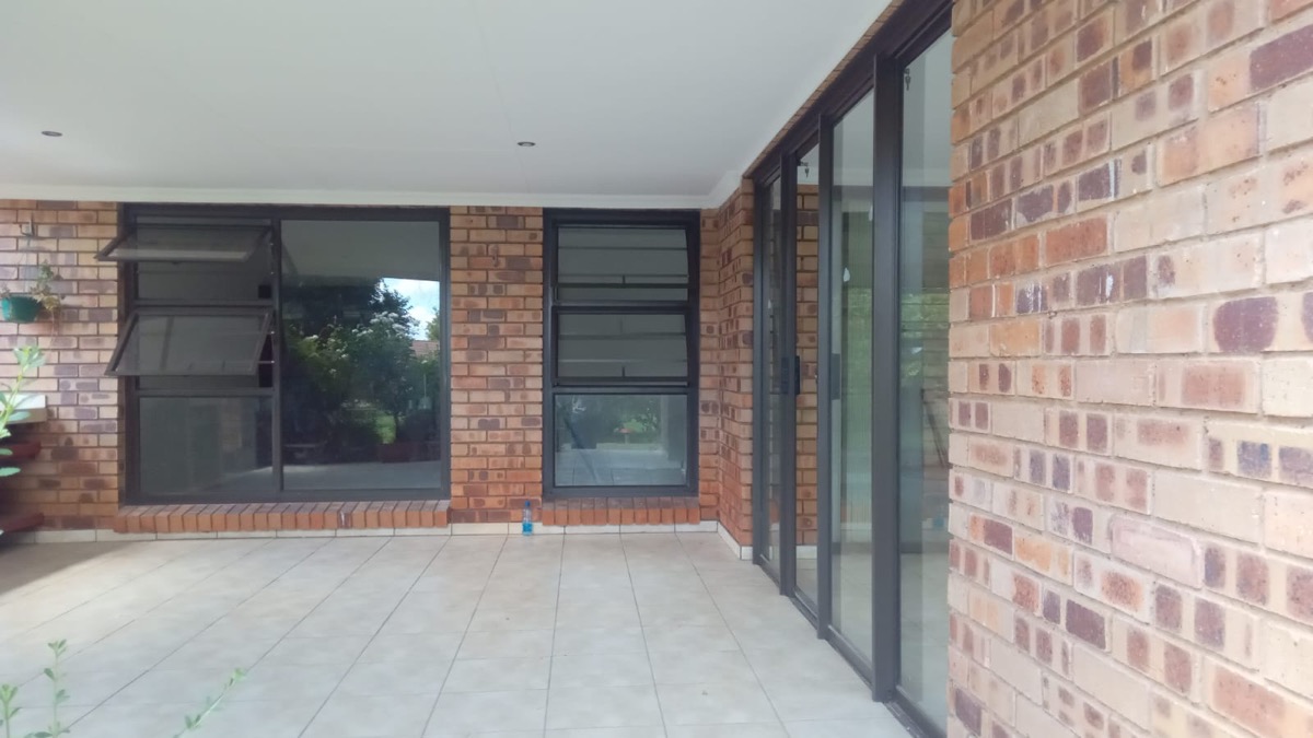 patio sliding doors with charcoal frames on a red brick home