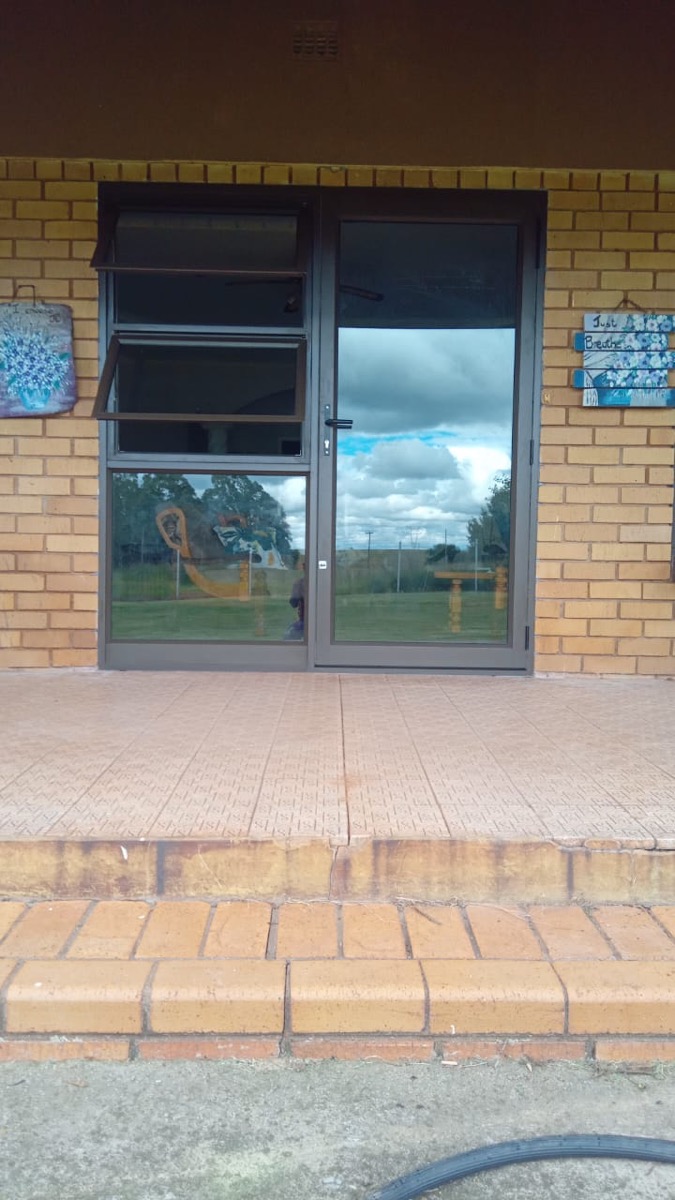 aluminium hinged entrance door with top-light on a brick building